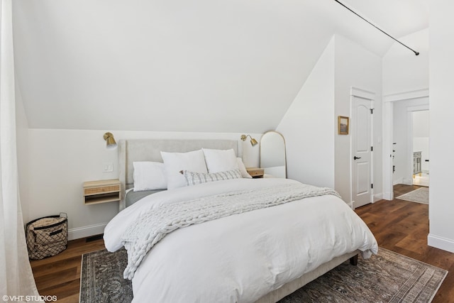 bedroom featuring lofted ceiling, dark wood-style flooring, and baseboards