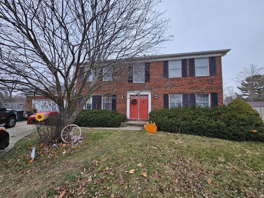 colonial house featuring brick siding and a front lawn