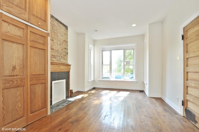 unfurnished living room featuring recessed lighting, a tile fireplace, baseboards, and wood finished floors