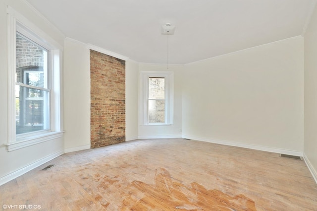 spare room with a wealth of natural light, ornamental molding, and light wood-type flooring
