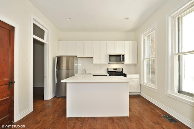 kitchen with white cabinets, stainless steel appliances, tasteful backsplash, and visible vents