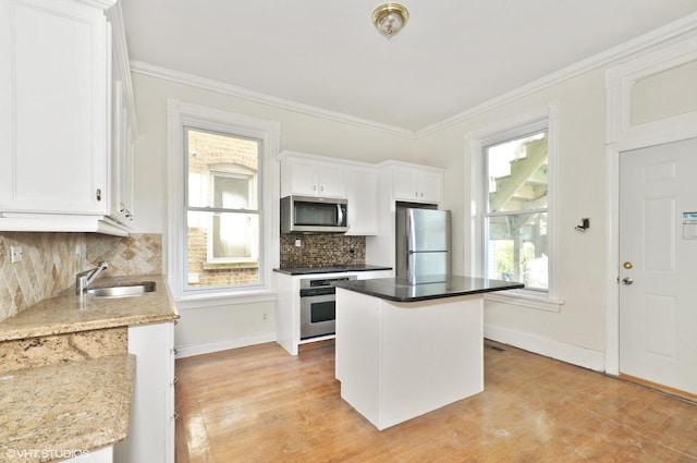 kitchen featuring white cabinetry, backsplash, appliances with stainless steel finishes, and a sink