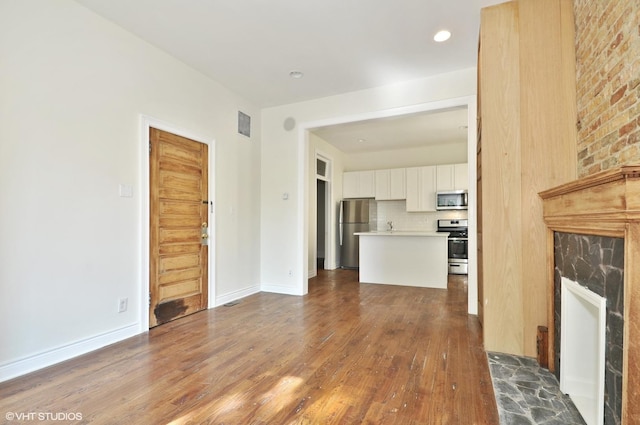 unfurnished living room featuring recessed lighting, baseboards, dark wood finished floors, visible vents, and a fireplace