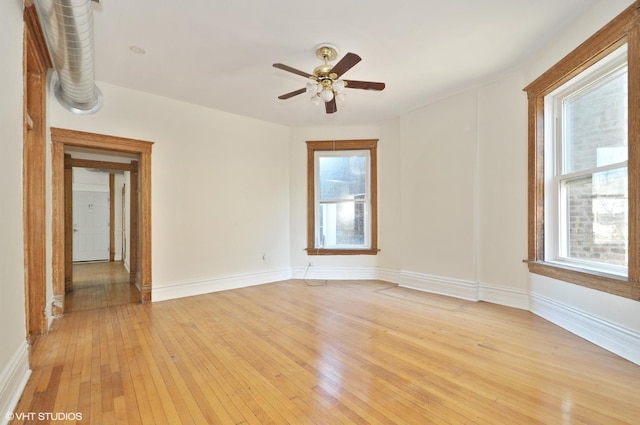 unfurnished room featuring light wood finished floors, a wealth of natural light, and baseboards