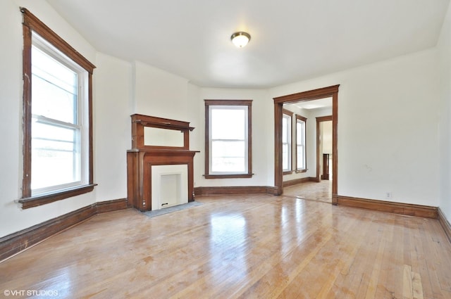 unfurnished living room with baseboards and hardwood / wood-style flooring