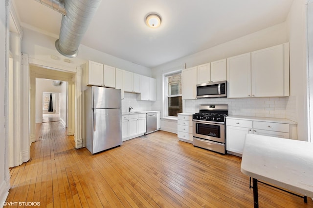 kitchen featuring white cabinets, light countertops, stainless steel appliances, and tasteful backsplash