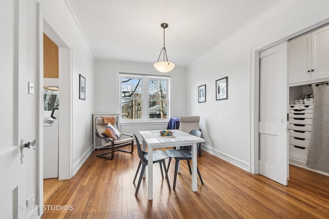 dining area featuring light wood-type flooring, baseboards, and ornamental molding