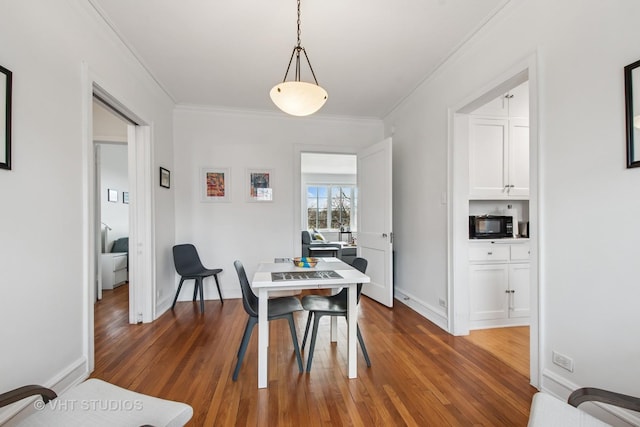 dining space featuring baseboards, dark wood finished floors, and crown molding