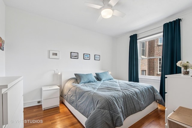 bedroom featuring ceiling fan, baseboards, and wood finished floors