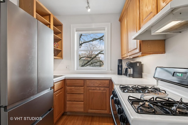 kitchen featuring open shelves, under cabinet range hood, freestanding refrigerator, and gas range