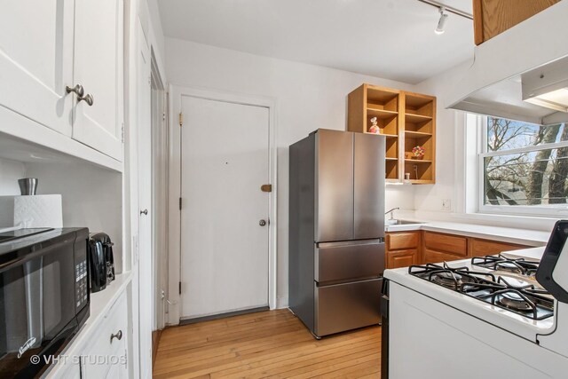 kitchen featuring white gas range, open shelves, freestanding refrigerator, black microwave, and light wood-type flooring