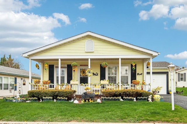 view of front of house featuring a porch, an attached garage, a front yard, and aphalt driveway