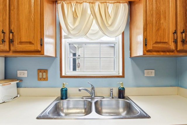kitchen with light countertops, brown cabinetry, and a sink