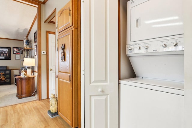 laundry room featuring laundry area, light wood-style flooring, and stacked washer / dryer