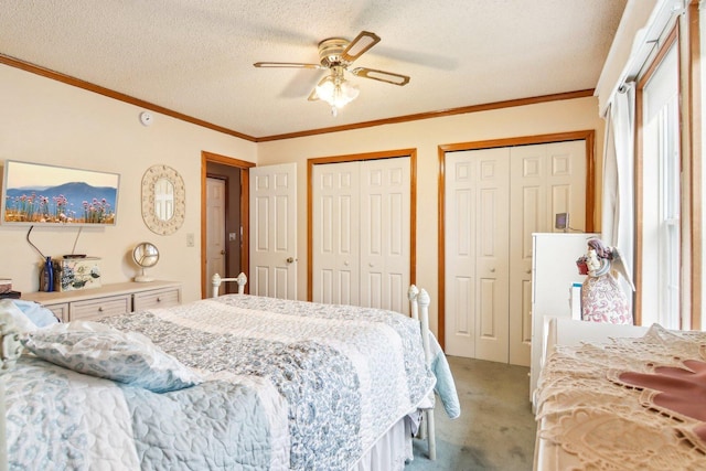 bedroom with crown molding, two closets, light colored carpet, a textured ceiling, and a ceiling fan