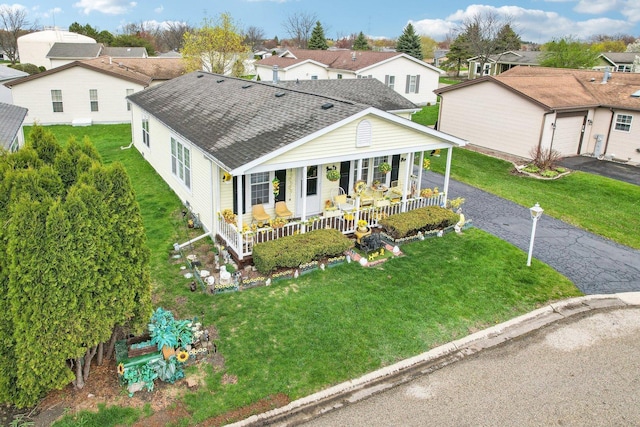 exterior space featuring covered porch, driveway, a residential view, and a shingled roof