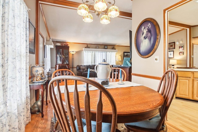 dining space featuring ornamental molding, light wood finished floors, and a notable chandelier