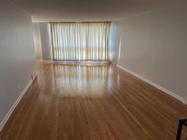 spare room featuring visible vents, baseboards, and wood finished floors