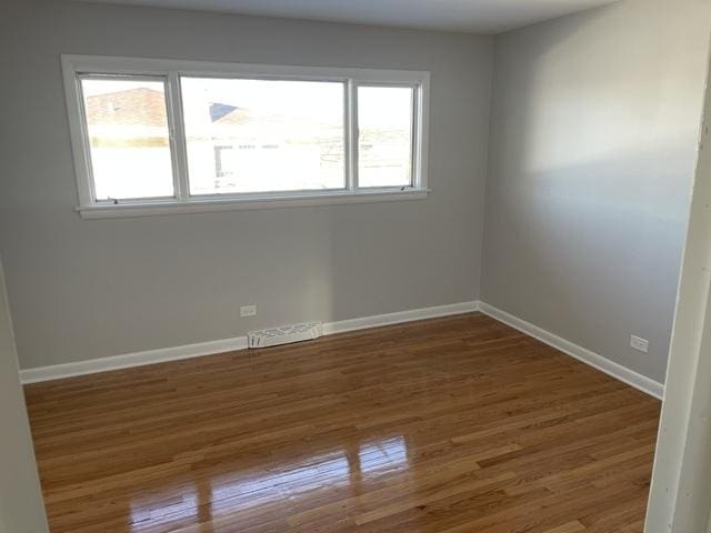 spare room featuring baseboards, visible vents, and wood finished floors