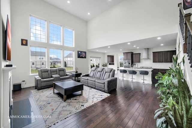 living area with dark wood-style flooring, recessed lighting, plenty of natural light, and a high ceiling