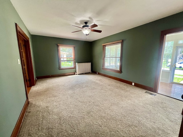 211 W 13th St, Sterling, IL 61081 - unfurnished room with radiator heating unit, carpet flooring, and plenty of natural light