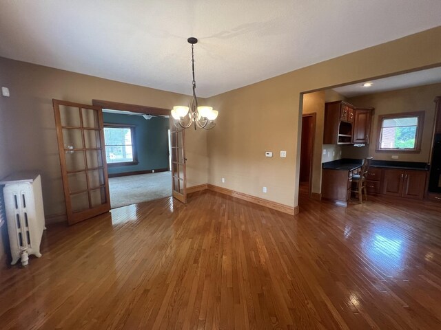 211 W 13th St, Sterling, IL 61081 - unfurnished dining area featuring radiator, wood finished floors, a chandelier, and baseboards