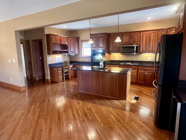 211 W 13th St, Sterling, IL 61081 - kitchen featuring stainless steel appliances, dark countertops, light wood-style floors, a center island, and open shelves