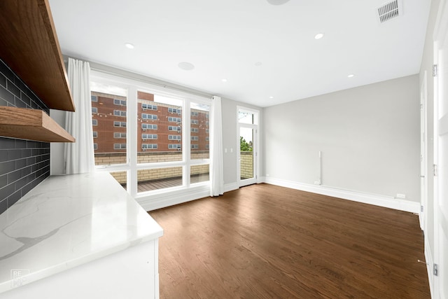 unfurnished living room with wood finished floors, baseboards, and recessed lighting