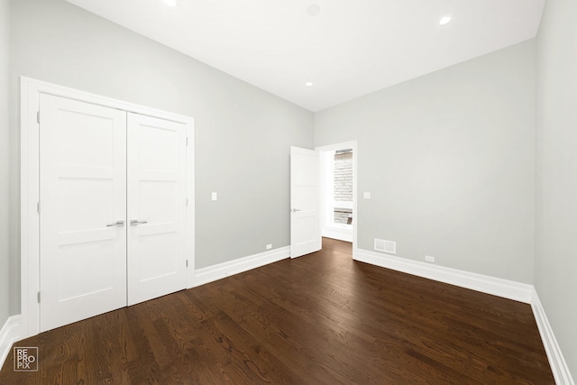 unfurnished bedroom with dark wood-style flooring, baseboards, a closet, and recessed lighting