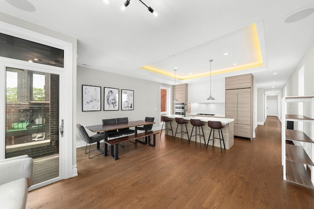 dining room featuring a tray ceiling, baseboards, dark wood finished floors, and recessed lighting