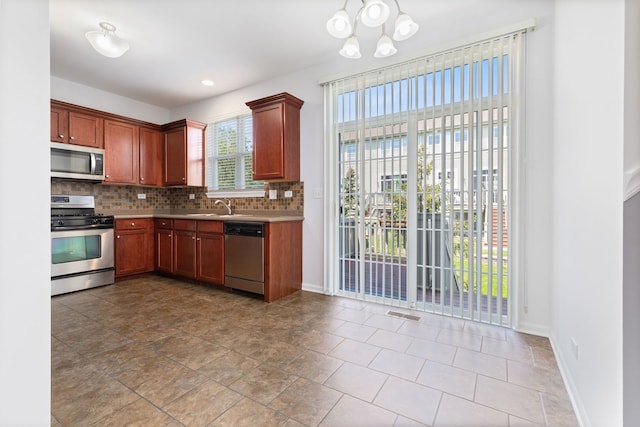 3576 Gabrielle Ln, Aurora, IL 60504 - kitchen featuring stainless steel appliances, tasteful backsplash, a chandelier, a sink, and baseboards