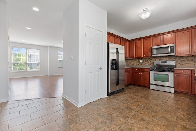 3576 Gabrielle Ln, Aurora, IL 60504 - kitchen featuring appliances with stainless steel finishes, backsplash, baseboards, open floor plan, and light countertops