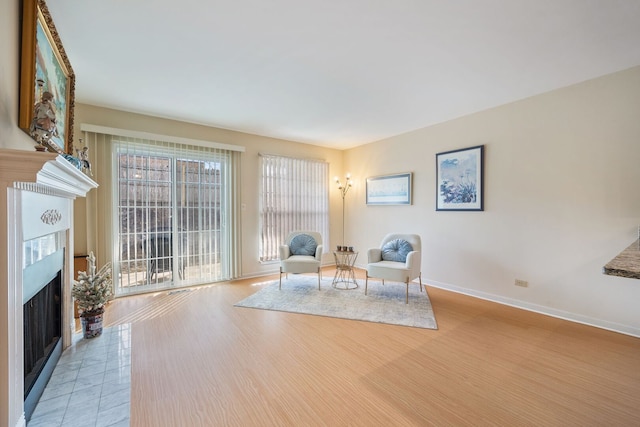 unfurnished room featuring a fireplace with flush hearth, baseboards, and light wood-type flooring