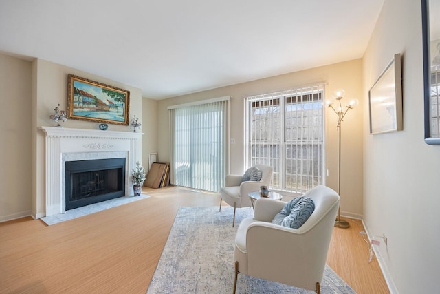 living area with a fireplace with flush hearth, baseboards, and wood finished floors
