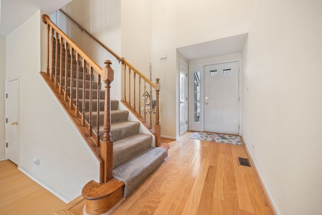 foyer featuring stairs, visible vents, light wood-style flooring, and baseboards