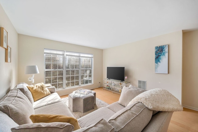 living room with baseboards, light wood-style floors, and visible vents