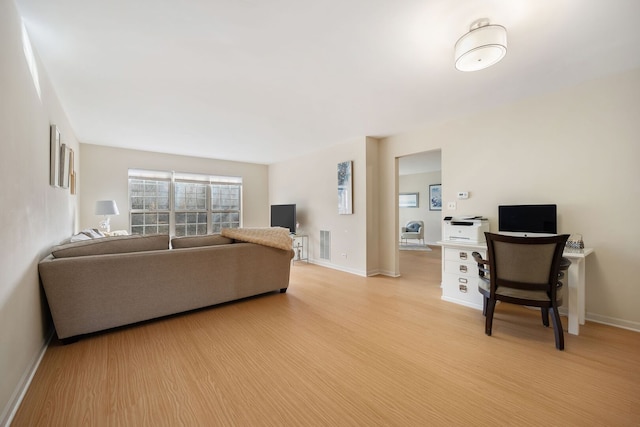 living room featuring light wood-style flooring, baseboards, and visible vents