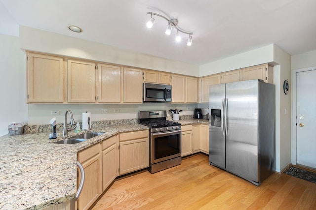 kitchen with a sink, light wood-type flooring, appliances with stainless steel finishes, and light brown cabinets