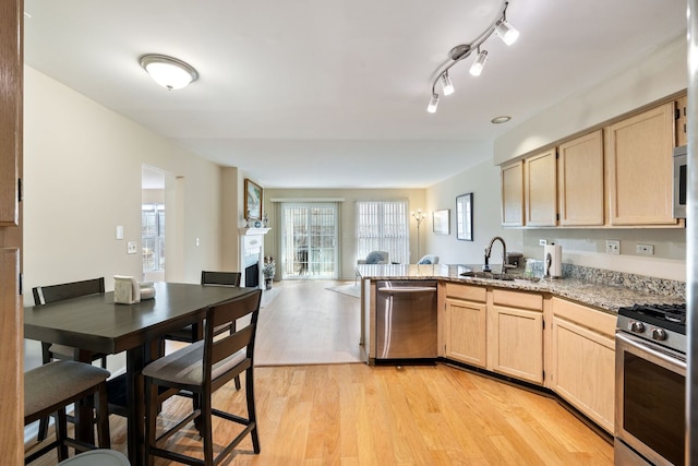 kitchen featuring a sink, light brown cabinetry, appliances with stainless steel finishes, and a peninsula