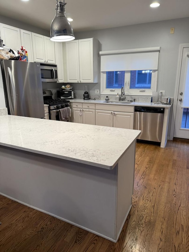 kitchen featuring light countertops, white cabinetry, stainless steel appliances, a sink, and wood finished floors