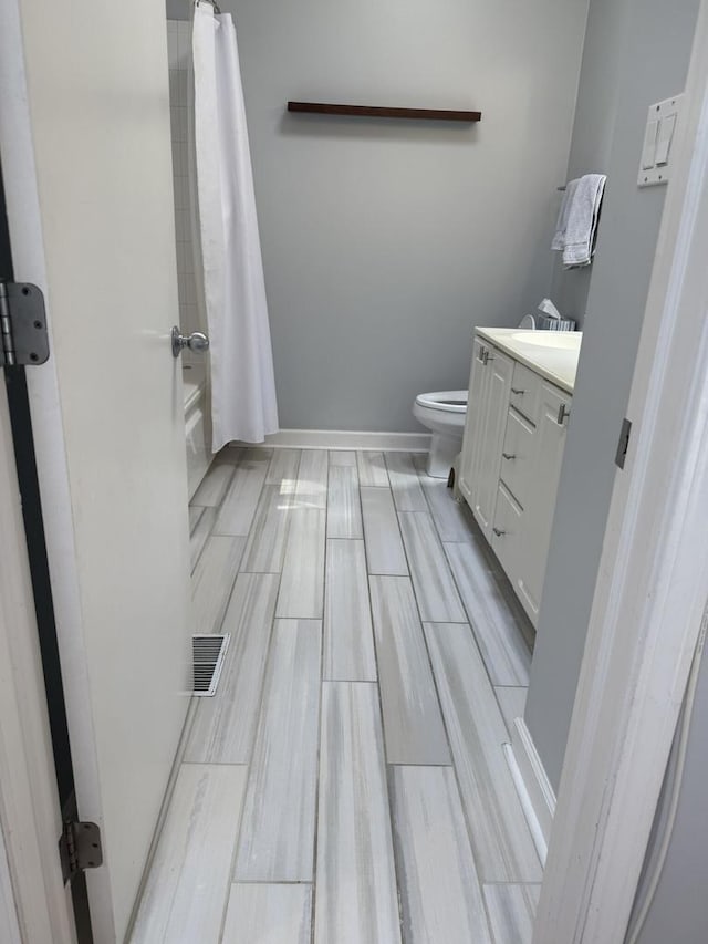 full bathroom with visible vents, baseboards, toilet, shower / bathtub combination with curtain, and vanity