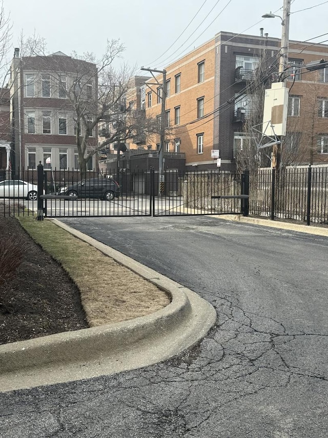 view of street featuring curbs, street lighting, a gated entry, and sidewalks