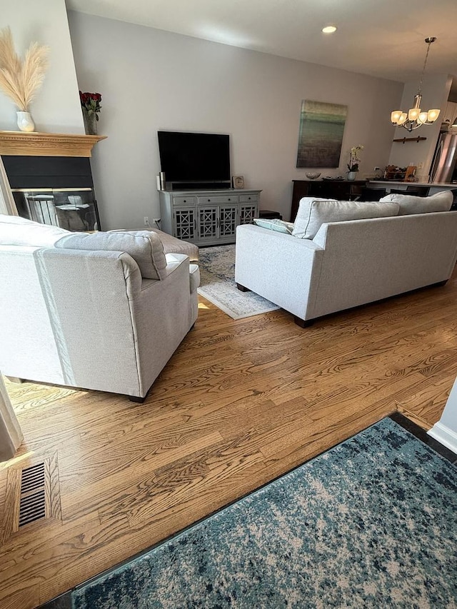 living room with visible vents, recessed lighting, an inviting chandelier, and wood finished floors