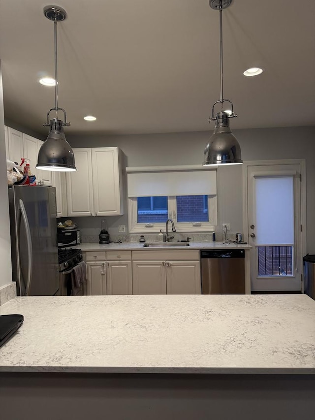 kitchen featuring light countertops, appliances with stainless steel finishes, a sink, and white cabinetry
