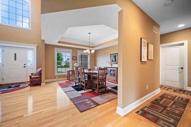 foyer featuring a notable chandelier, baseboards, visible vents, wood finished floors, and a raised ceiling