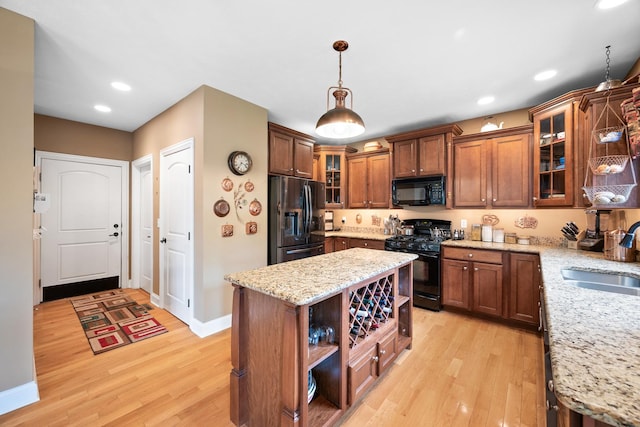 kitchen featuring a sink, open shelves, light wood-type flooring, black appliances, and baseboards
