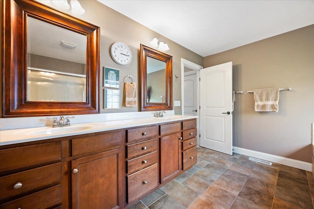 full bath featuring baseboards, visible vents, a sink, and double vanity