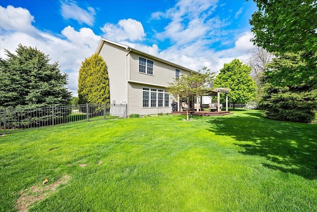 back of house featuring fence, a wooden deck, and a lawn