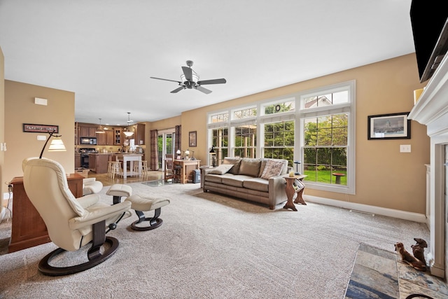 living room with a wealth of natural light, light carpet, and ceiling fan