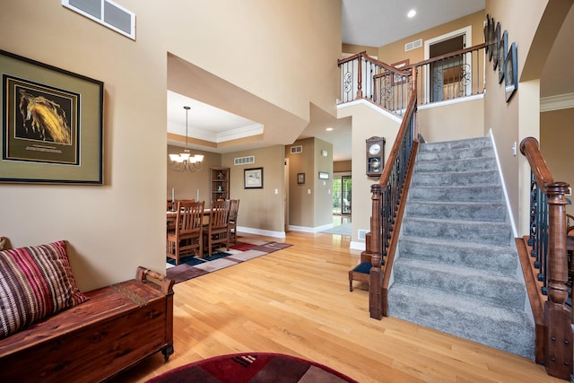 staircase with an inviting chandelier, visible vents, and wood finished floors